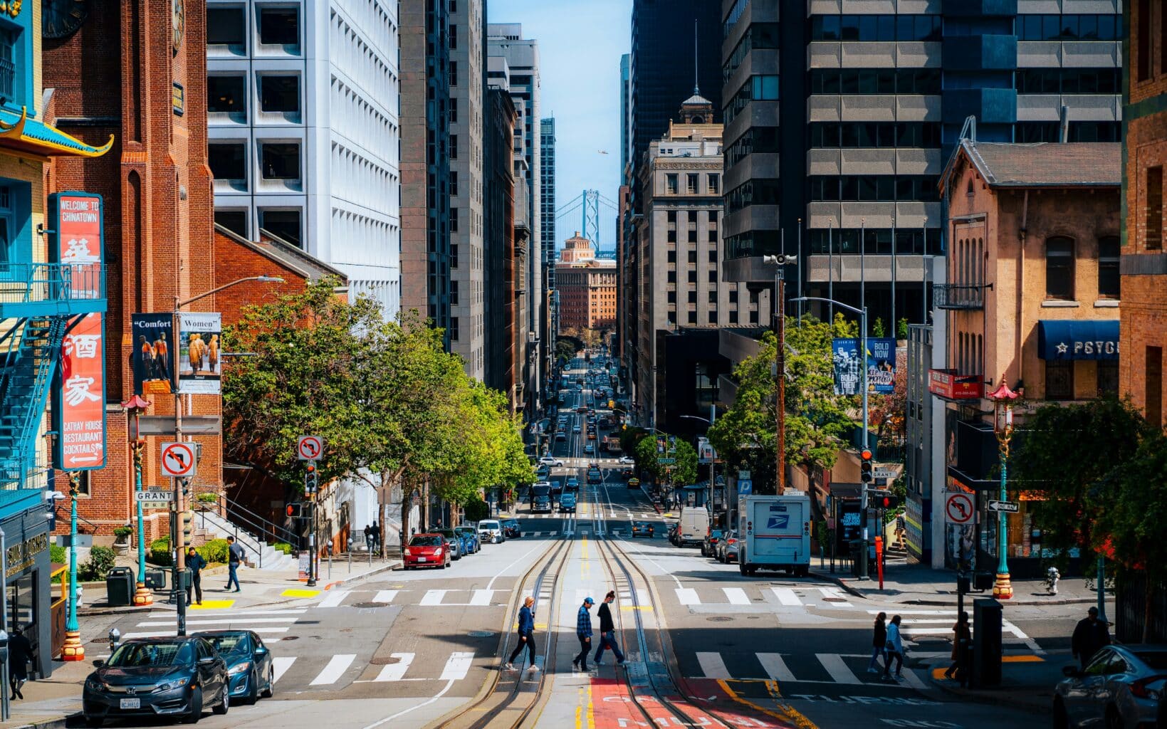 People walking across a busy city intersection in downtown San Francisco.